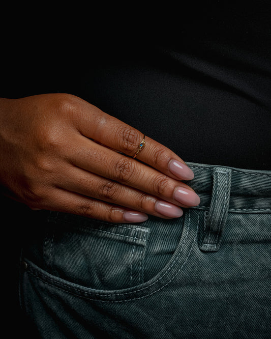 Hand adjusting a black shirt with a visible ring on a dark background