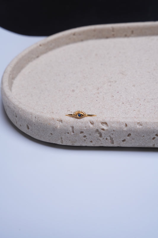 Gold ring with a blue gemstone on a textured beige surface